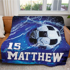 Soccer throw blanket laid flat across bedroom bed displaying vibrant blue sports artwork